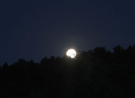 Mond beim Versuch sich hinter Hochspannungsmast zu verstecken