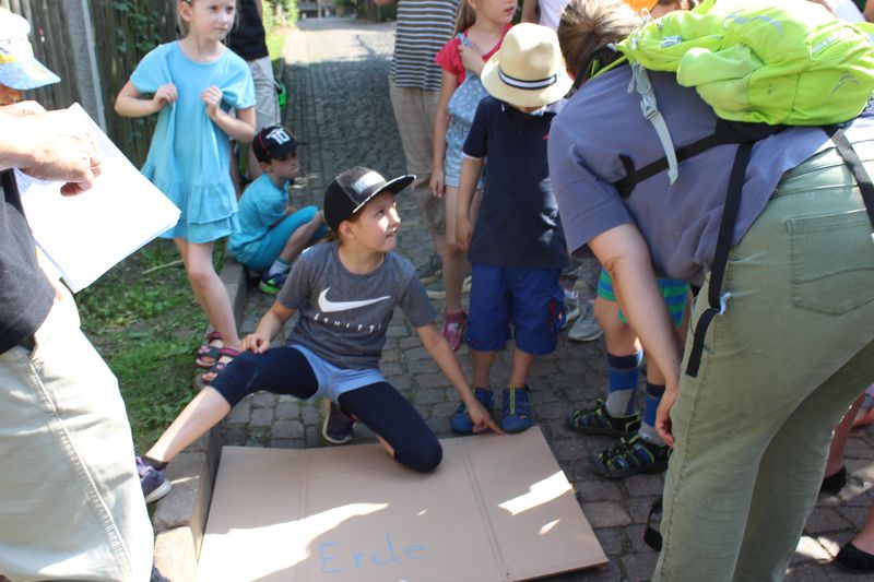 Kinder & Erwachsene diskutieren an der aufgemalten Erde, wo die ISS ungefähr fliegt