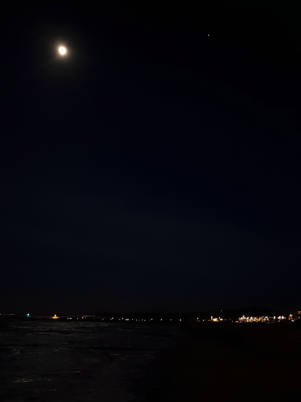 vergrößerter Abstand zwischen dem Mond und Jupiter über dem dunklen Ostseestrand