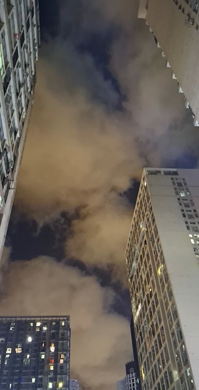 Blick zwischen Hochhäuser in den Abendhimmel mit hell leuchtenden Wolken und einzelnen Lücken