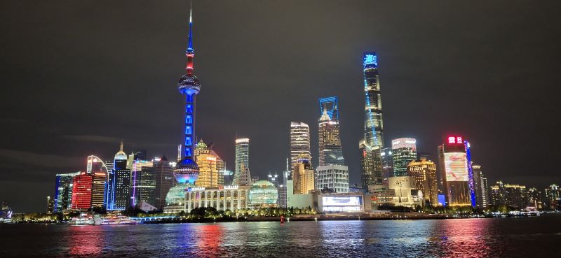 bunte Skyline der auf der Pudongseite befindlichen Wolkenkratzer und des Pearltowers mit sich im Wasser spiegelnden Lichtern