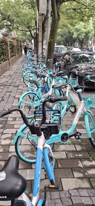 unzählige hellblaue Leihfahrräder an Rand auf dem Bürgersteig