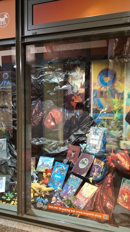 Schaufensterdeko zum Thema Drachen mit Büchern, Kostümen und Plüschtieren