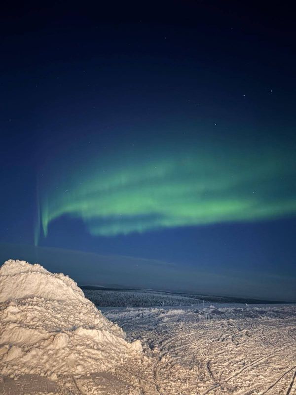 Schneelandschaft mit großflächigem grünem Polarlicht  