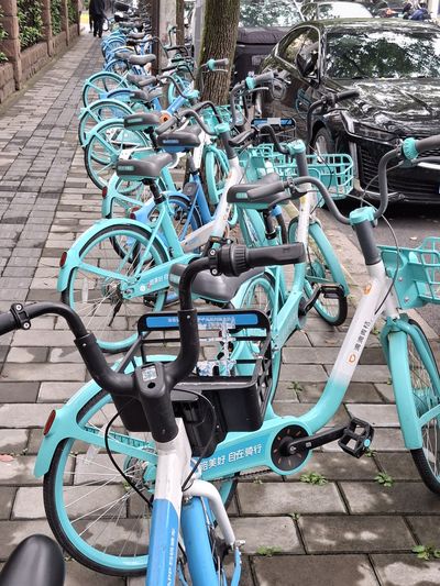 viele hellblaue Leihfahrräder am Straßenrand