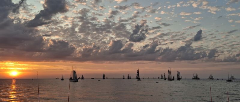 Blick auf die Ostsee mit vielen Segelbooten und der untergehenden orangefarbenen Sonne